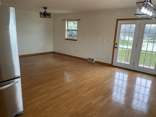 unfurnished dining area with baseboards, wood finished floors, and visible vents