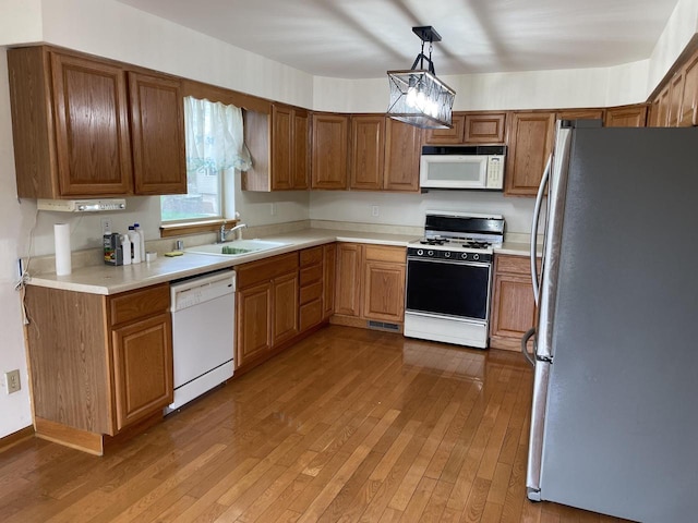 kitchen with light countertops, visible vents, a sink, white appliances, and light wood-style flooring