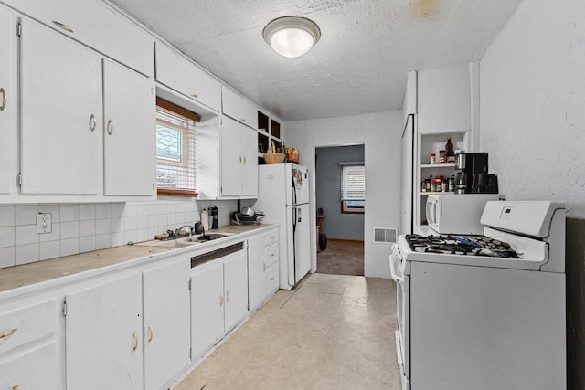 kitchen featuring white cabinets, a textured ceiling, and white appliances