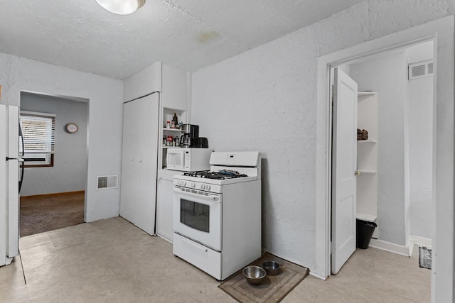 kitchen featuring visible vents, a textured wall, white appliances, and a textured ceiling