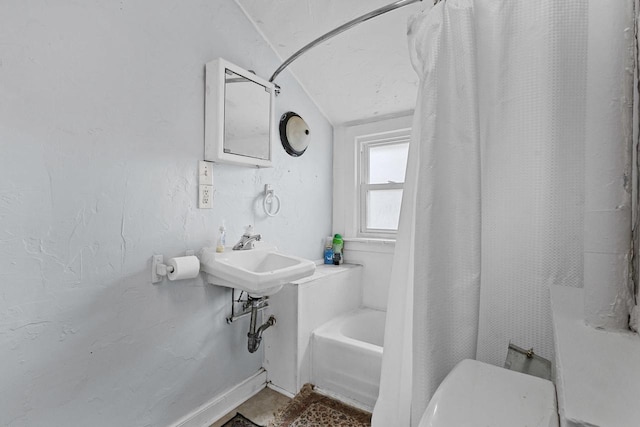 bathroom with lofted ceiling, shower / bath combination with curtain, toilet, a sink, and baseboards
