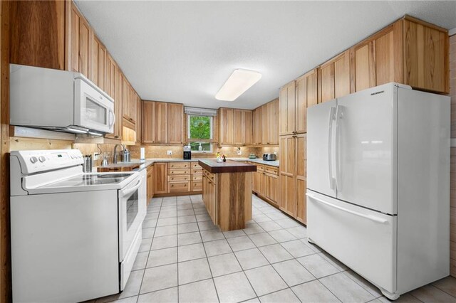 6756 Deer Track Rd, Siren, WI 54872 - kitchen featuring a center island, a sink, light tile patterned flooring, white appliances, and backsplash