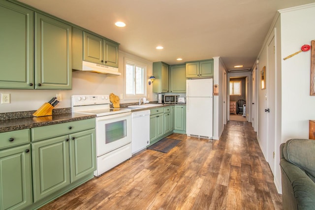 kitchen featuring a sink, under cabinet range hood, recessed lighting, white appliances, and dark wood-type flooring
