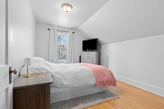 bedroom featuring vaulted ceiling, wood finished floors, and baseboards