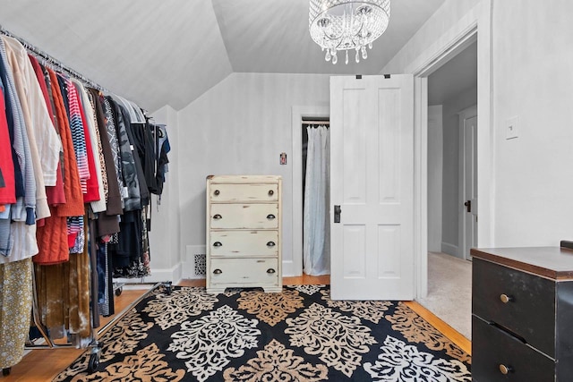 spacious closet with lofted ceiling, wood finished floors, and a chandelier