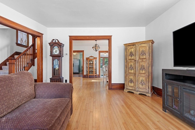 living area with baseboards, stairs, and light wood-style flooring