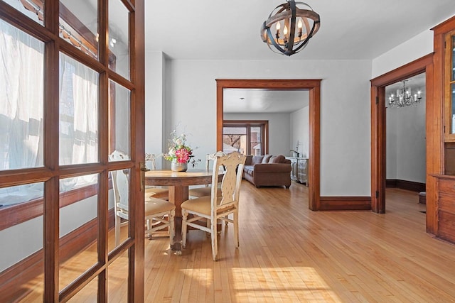 dining space with baseboards, a notable chandelier, and light wood-type flooring