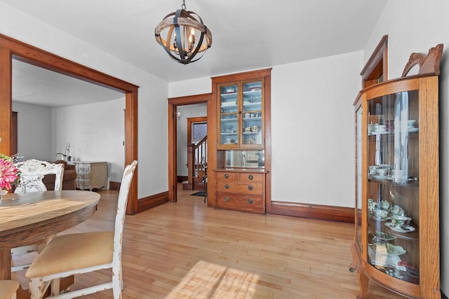 dining space with light wood-type flooring, baseboards, and a chandelier