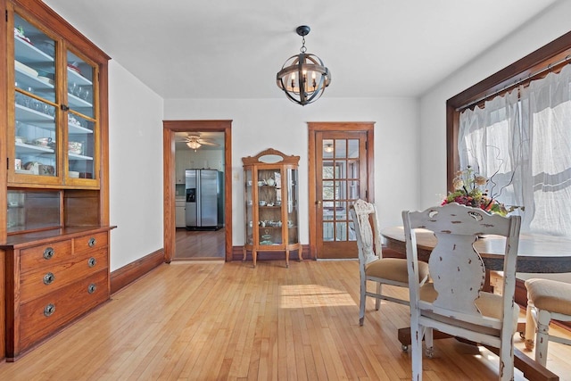 dining area featuring baseboards, ceiling fan with notable chandelier, and light wood-type flooring