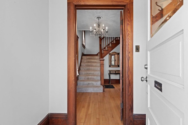 interior space with baseboards, an inviting chandelier, light wood-style floors, and stairway