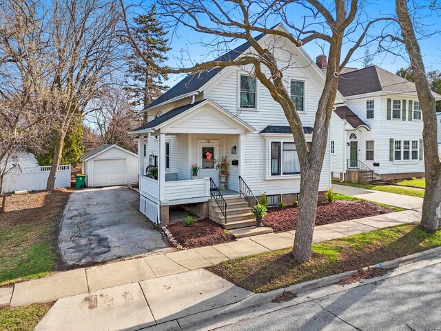 view of front facade featuring driveway, an outdoor structure, covered porch, and a detached garage