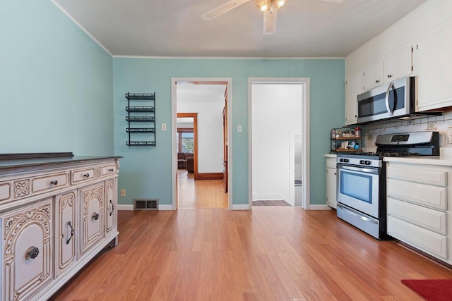 kitchen with stainless steel appliances, light wood-type flooring, visible vents, backsplash, and a ceiling fan