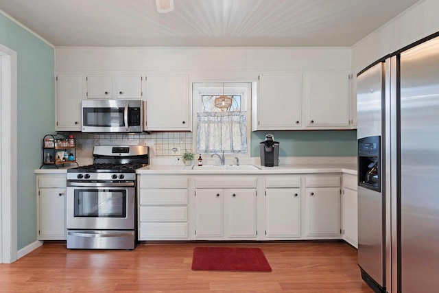 kitchen featuring stainless steel appliances, a sink, light wood-type flooring, white cabinetry, and light countertops