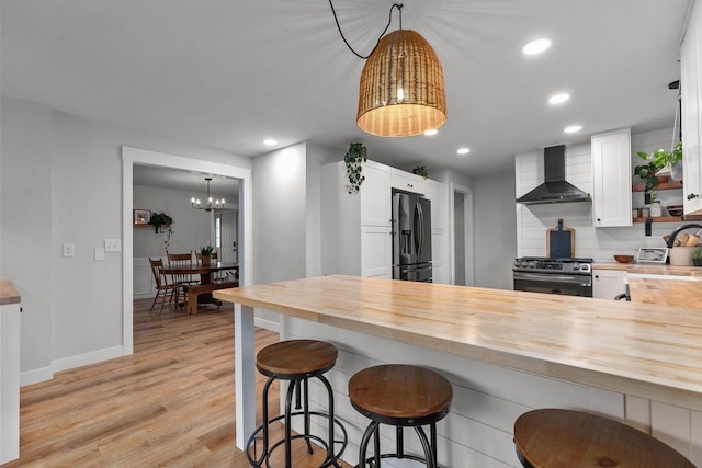 1620 E Murdock Ave, Oshkosh, WI 54901 - kitchen featuring wall chimney range hood, wooden counters, a chandelier, fridge with ice dispenser, and stainless steel gas stove