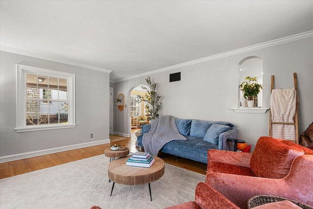 living area with crown molding, wood finished floors, arched walkways, baseboards, and visible vents