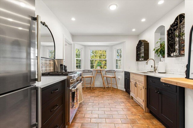 kitchen with a sink, recessed lighting, decorative backsplash, light countertops, and appliances with stainless steel finishes
