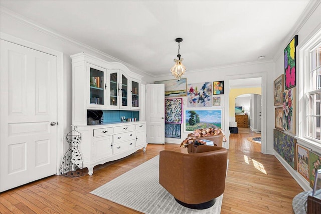 sitting room with light wood-style flooring, arched walkways, a chandelier, and crown molding