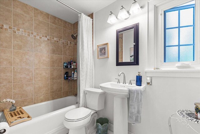 bathroom featuring toilet, shower / bath combo, and a sink
