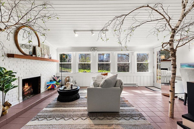 tiled living area with baseboard heating, a brick fireplace, and a healthy amount of sunlight