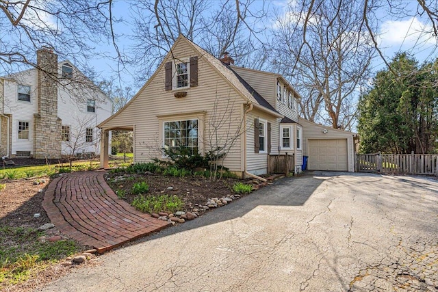 view of front of house with a chimney, fence, aphalt driveway, and a garage