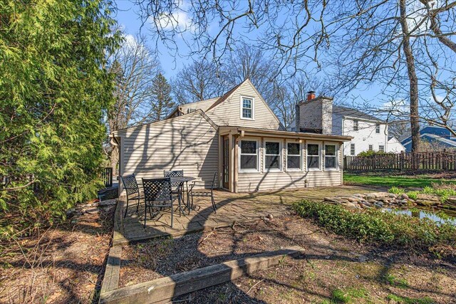 rear view of property with fence, a chimney, and a patio