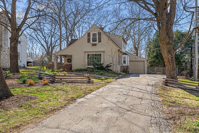 view of front of property with a detached garage, aphalt driveway, and fence
