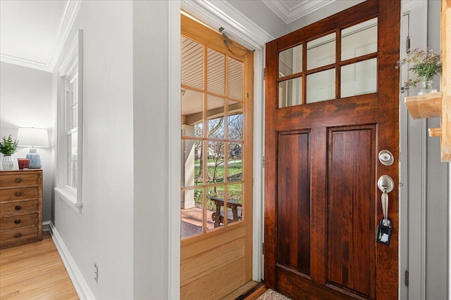 doorway to outside featuring baseboards, ornamental molding, and light wood finished floors