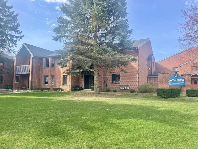 rear view of property featuring brick siding and a yard