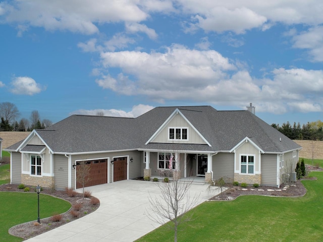 N56W27213 Crispin Ct, Lisbon, WI 53089 - view of front facade featuring a front lawn, driveway, stone siding, a garage, and a shingled roof