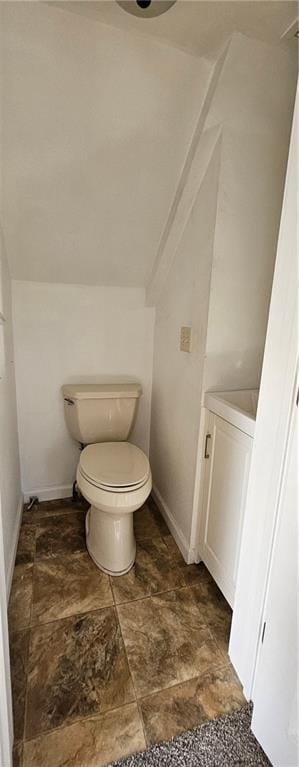 bathroom with baseboards, stone finish flooring, and toilet