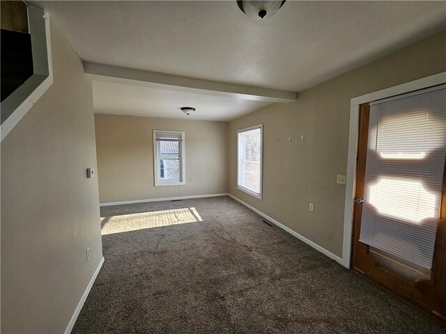 unfurnished room with baseboards, beamed ceiling, and carpet flooring
