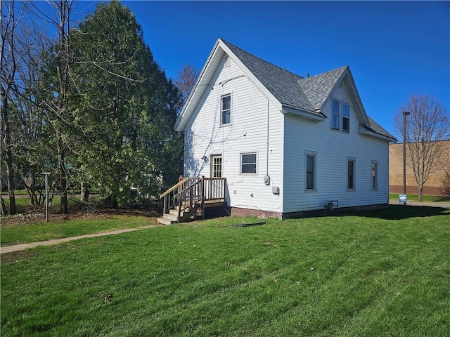 rear view of property featuring a lawn and a shingled roof