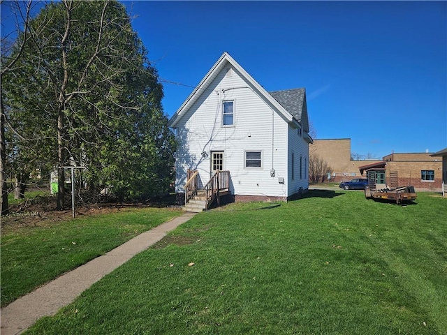 back of property featuring a lawn and a shingled roof