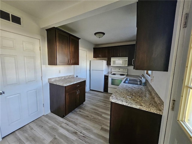 kitchen featuring a sink, dark brown cabinets, white appliances, and visible vents