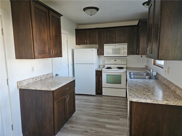 kitchen featuring a sink, dark brown cabinetry, white appliances, and light wood-type flooring