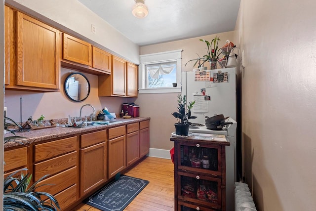 303 N Ashland Ave, Green Bay, WI 54303 - kitchen with radiator, light wood-style floors, brown cabinetry, and a sink