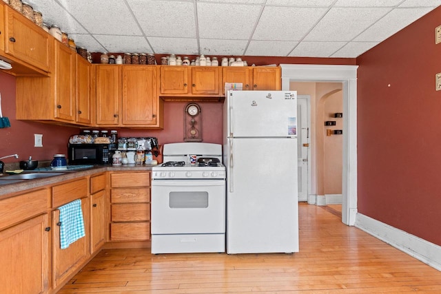 303 N Ashland Ave, Green Bay, WI 54303 - kitchen featuring brown cabinets, light wood finished floors, white appliances, arched walkways, and baseboards