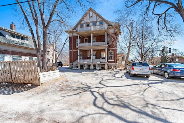 303 N Ashland Ave, Green Bay, WI 54303 - view of front of home with brick siding, a balcony, covered porch, and fence