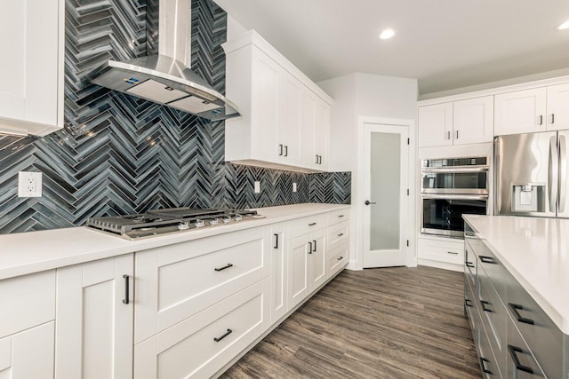 kitchen featuring wall chimney range hood, appliances with stainless steel finishes, tasteful backsplash, and light countertops