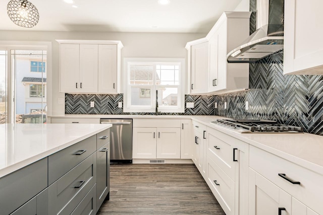 kitchen featuring light countertops, gray cabinets, wall chimney exhaust hood, white cabinetry, and stainless steel appliances