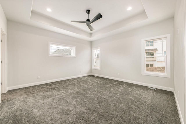 unfurnished room featuring carpet flooring, a tray ceiling, baseboards, and ceiling fan