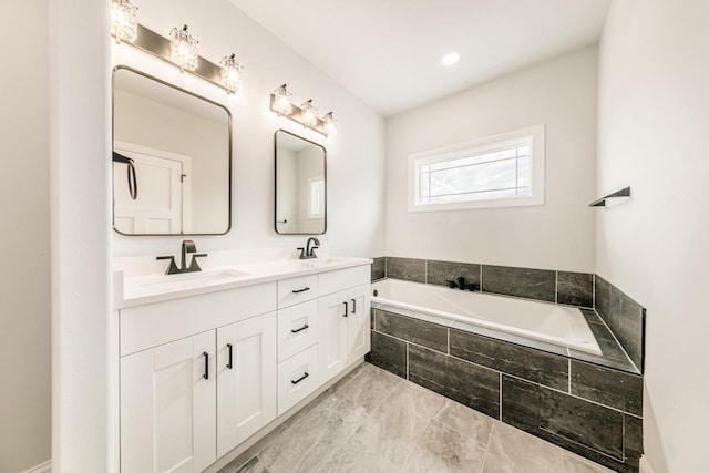 bathroom with double vanity, a sink, marble finish floor, and a garden tub