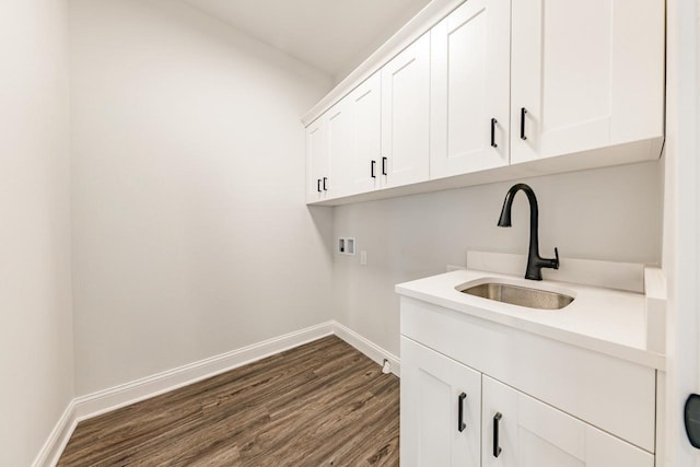 laundry area with dark wood finished floors, cabinet space, a sink, baseboards, and hookup for a washing machine