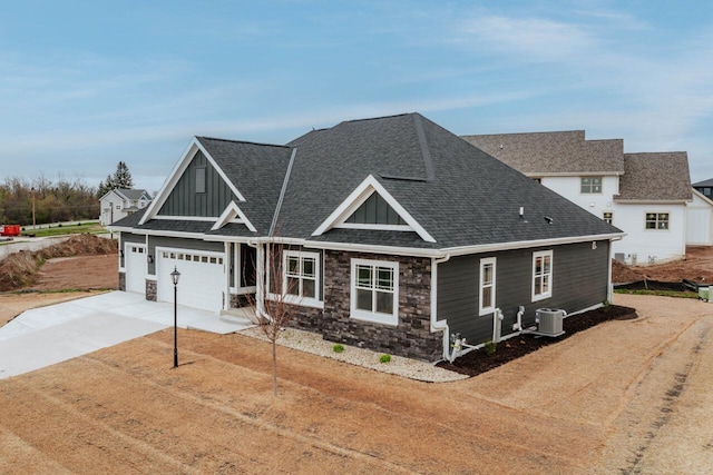 craftsman-style home featuring board and batten siding, central air condition unit, driveway, and stone siding