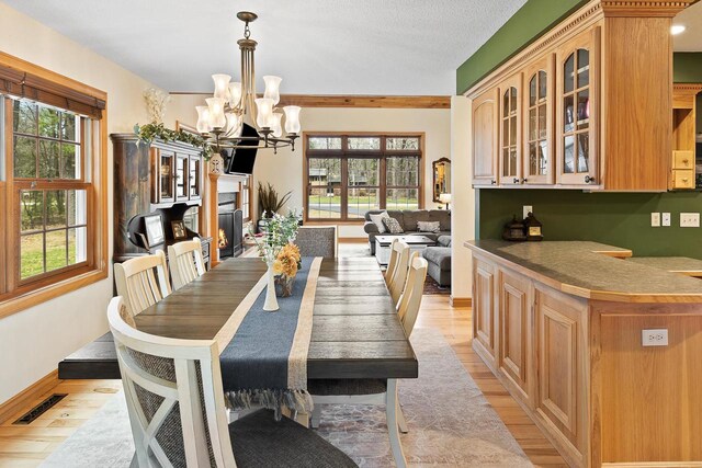 dining space with light wood finished floors, baseboards, visible vents, and a chandelier