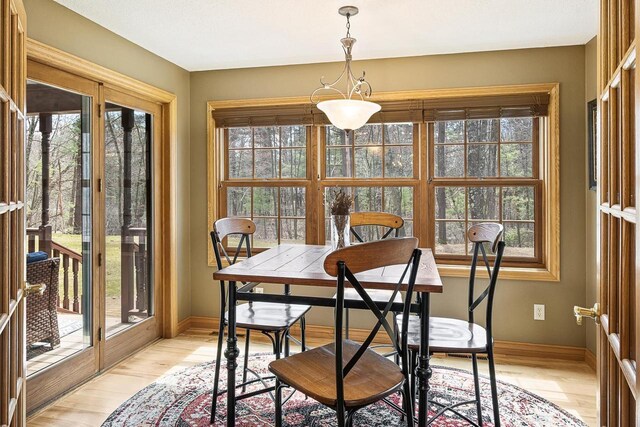 dining space with light wood-type flooring and baseboards