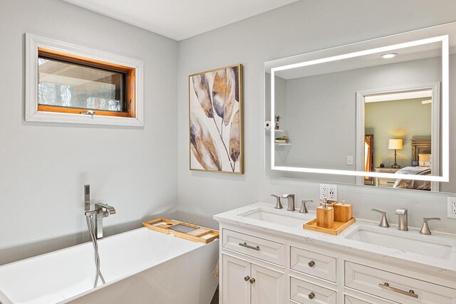 full bath with ensuite bath, a freestanding tub, a sink, and double vanity