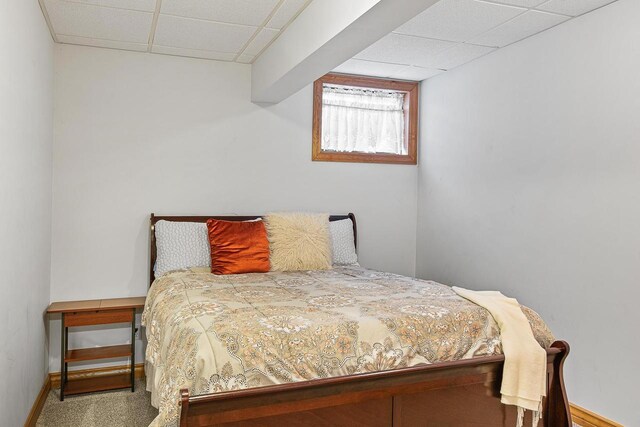 bedroom with baseboards, carpet flooring, and a paneled ceiling
