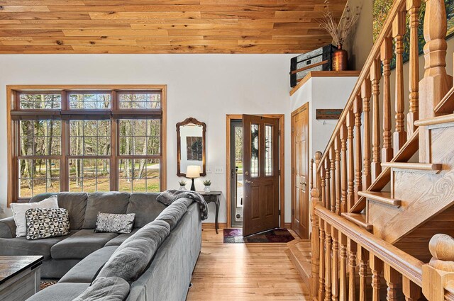 entryway with stairs, a high ceiling, wood ceiling, light wood-style flooring, and baseboards