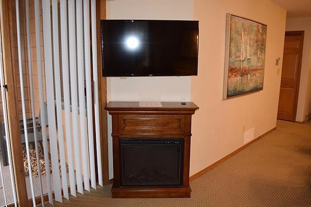 living area with a glass covered fireplace, visible vents, carpet flooring, and baseboards